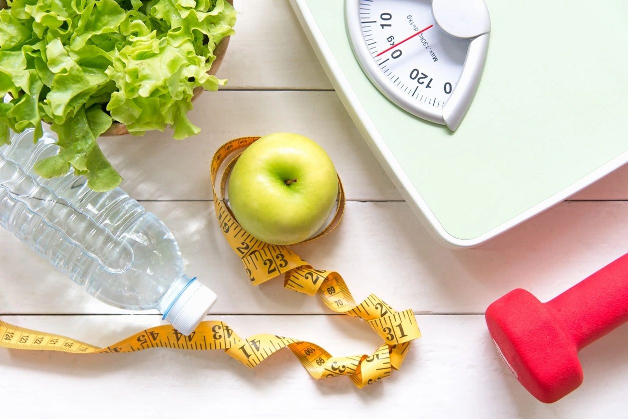 Health and fitness items including apple, scale, and dumbbell